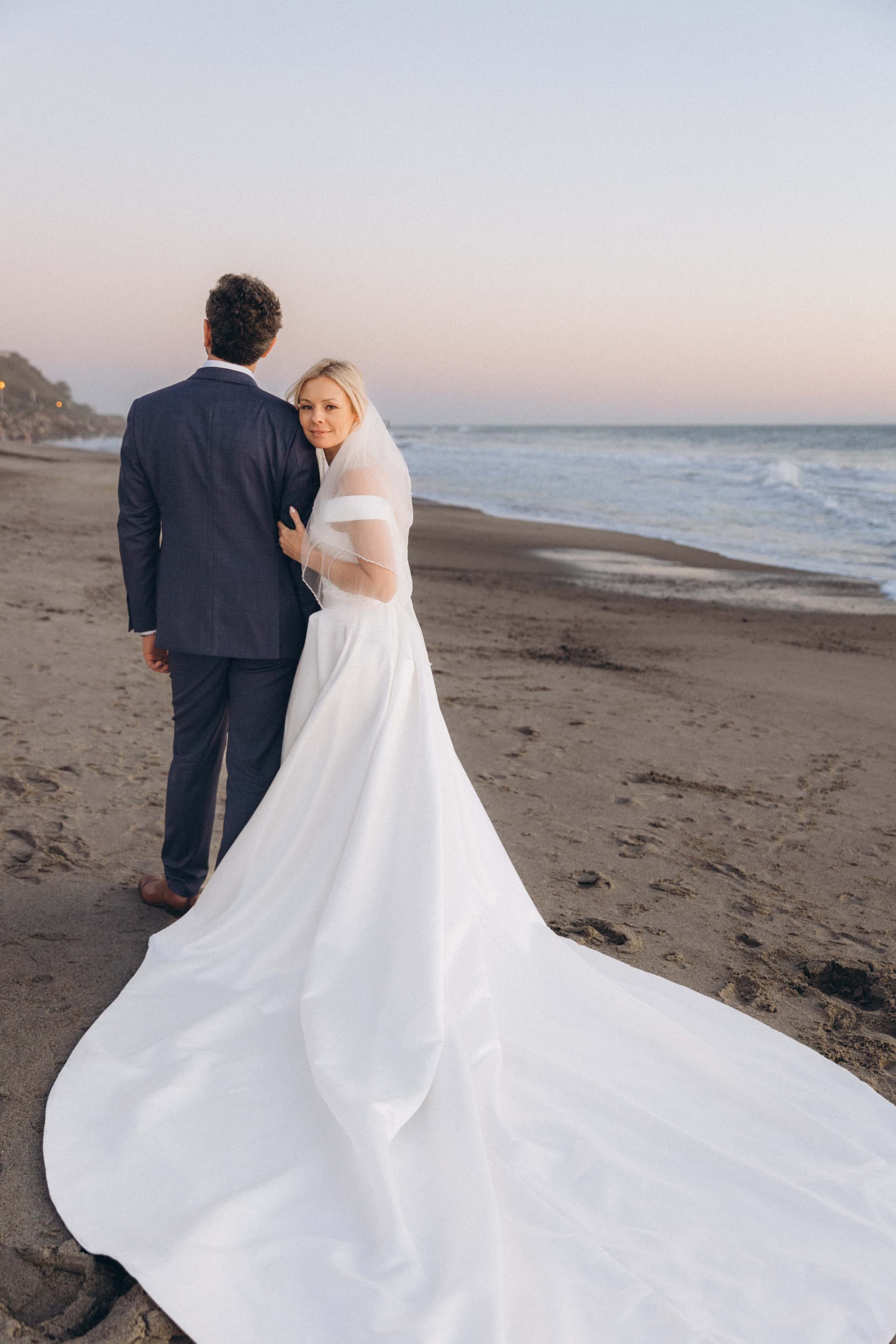 Bride looking back on beach with long train