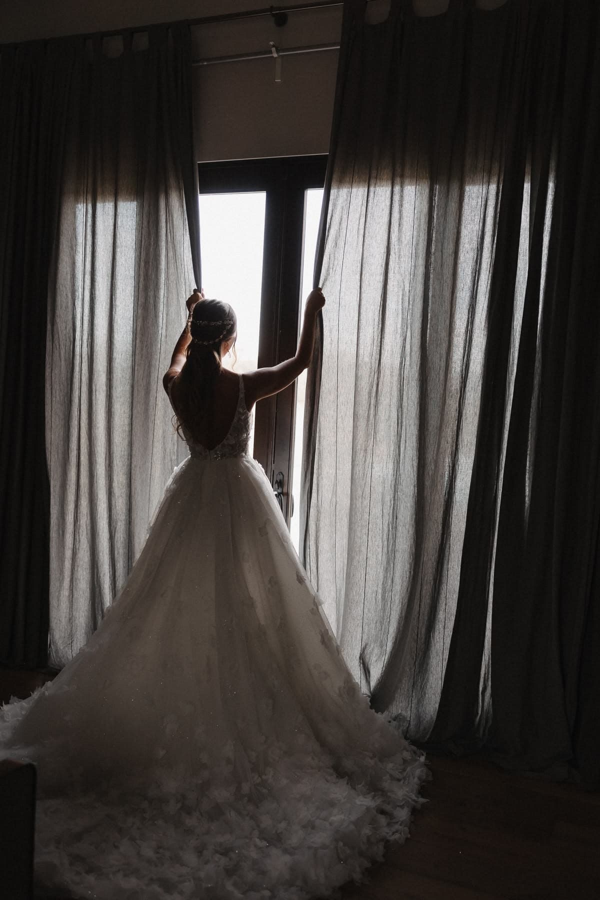 Bride opening curtains in ball gown silhouette