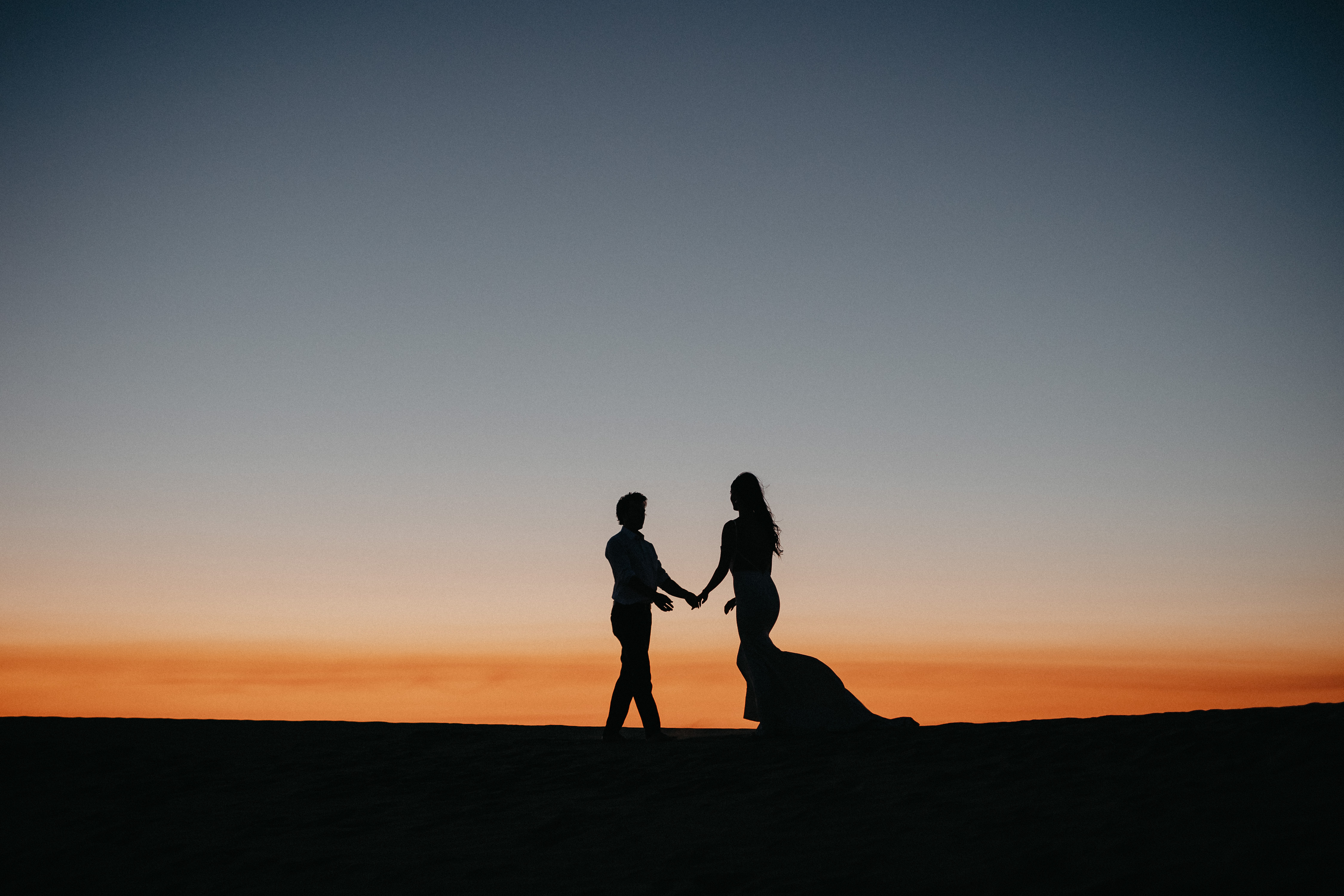 Couple silhouette holding hands at sunset