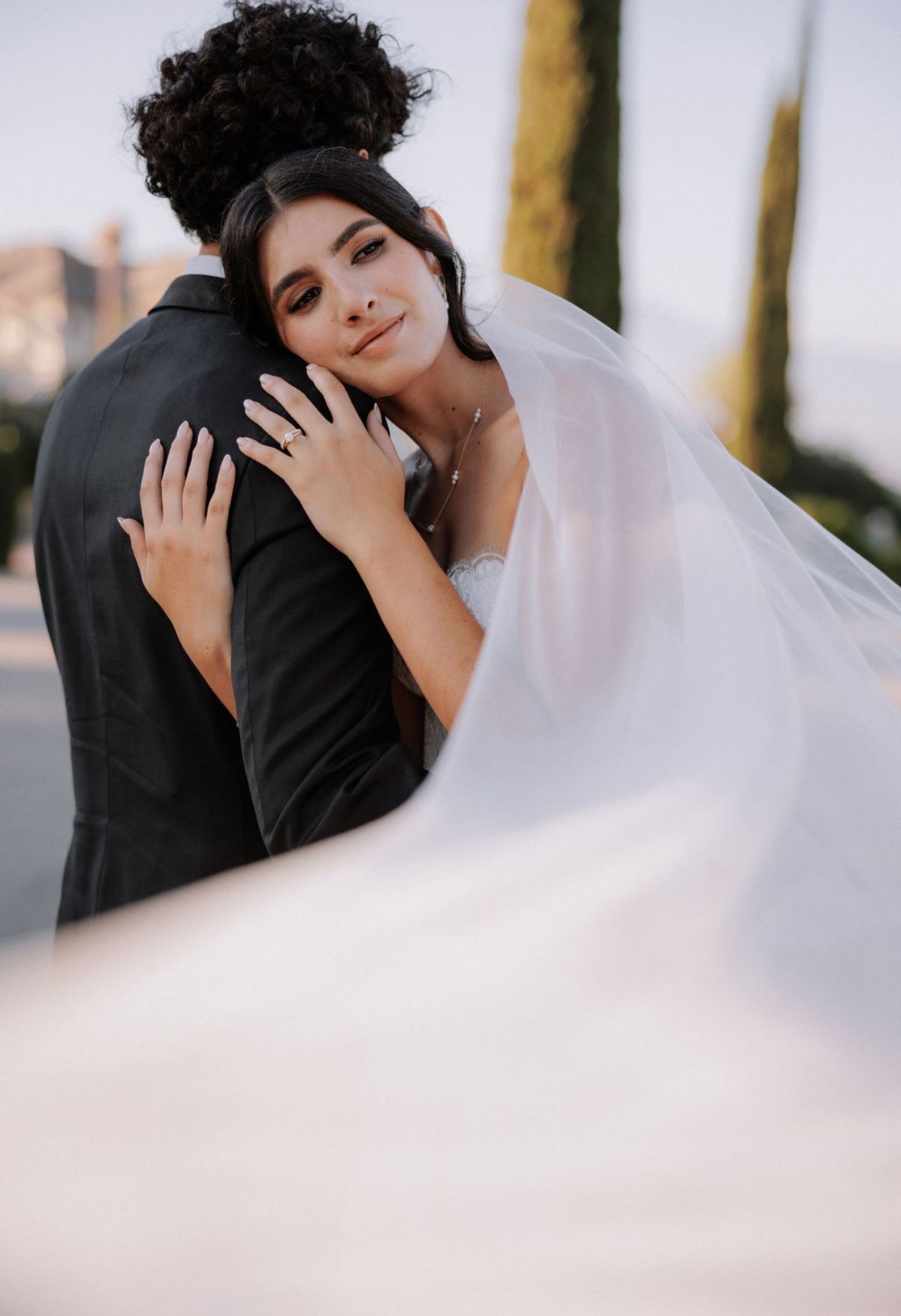 Bride embracing groom with flowing veil