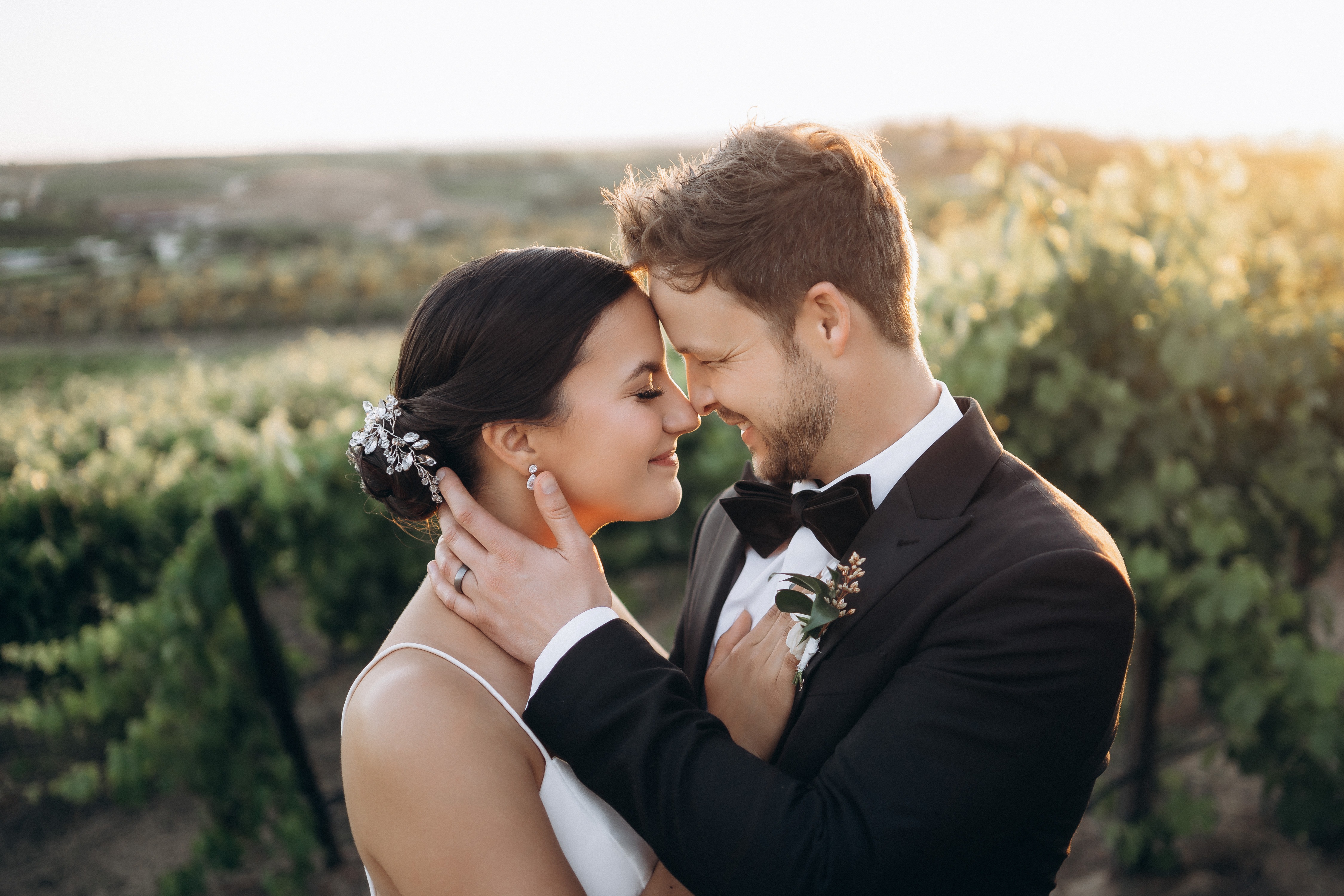 Couple touching foreheads in vineyard at golden hour