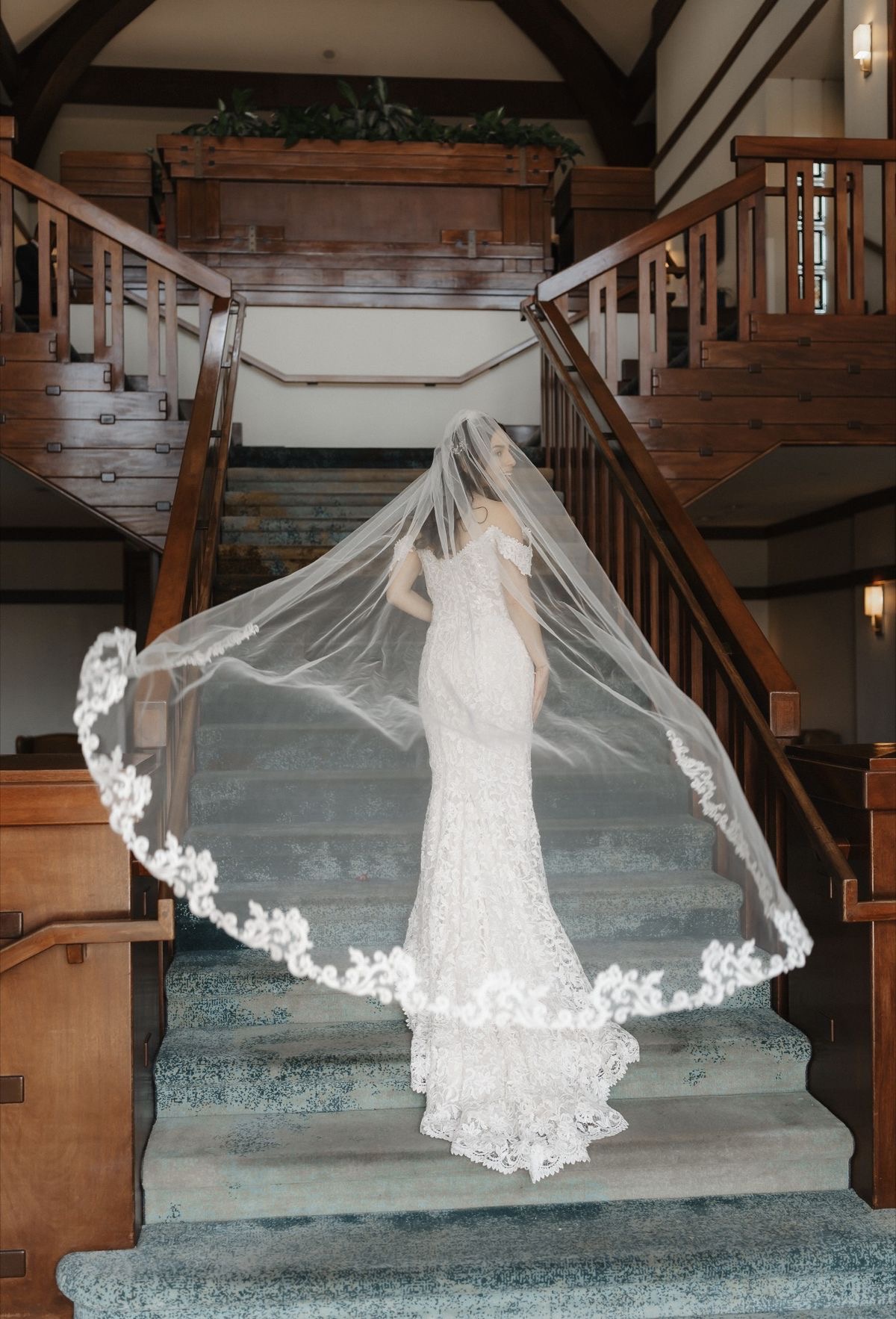 Bride on grand staircase with flowing lace veil