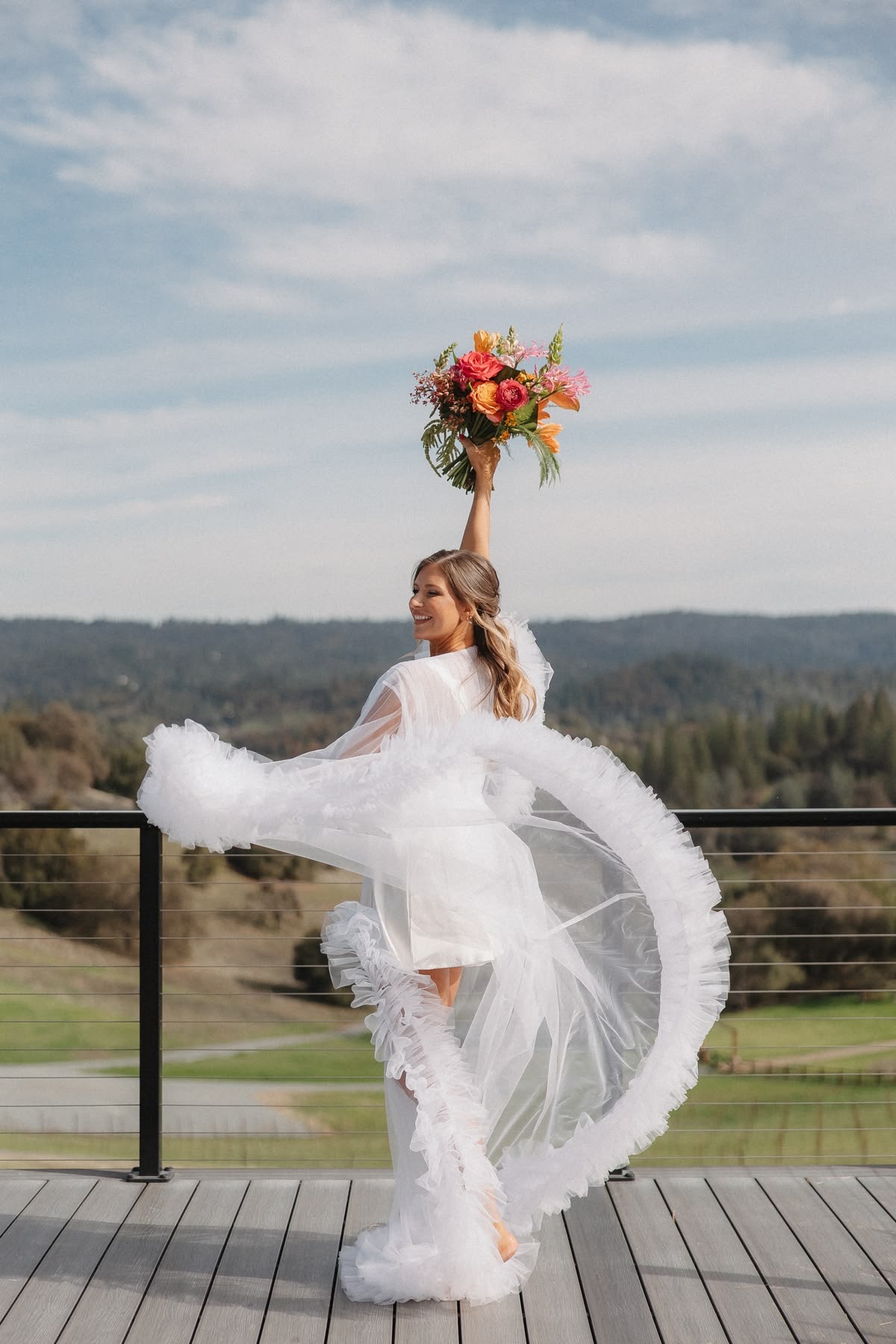 Bride on deck with colorful bouquet and tulle robe