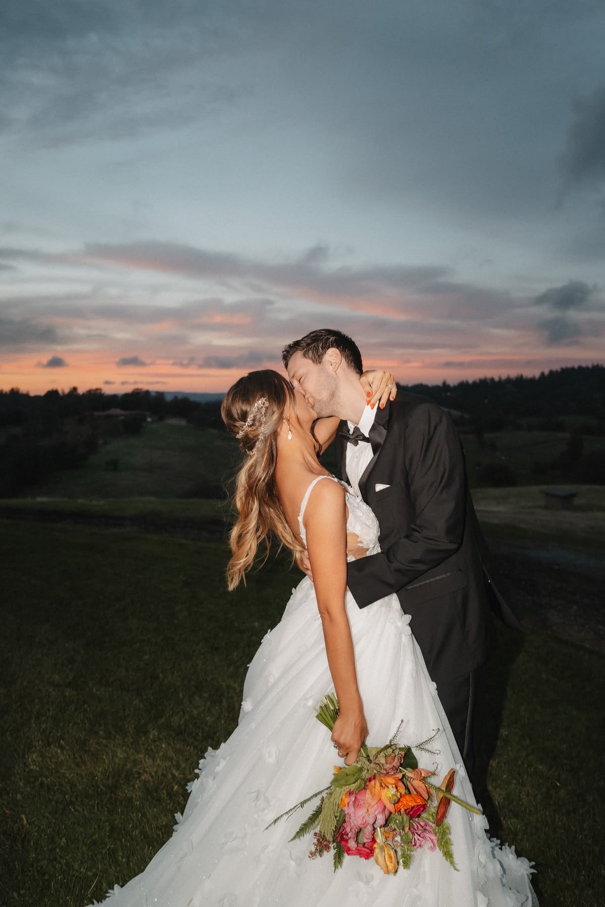 Couple kissing at dusk with colorful bouquet