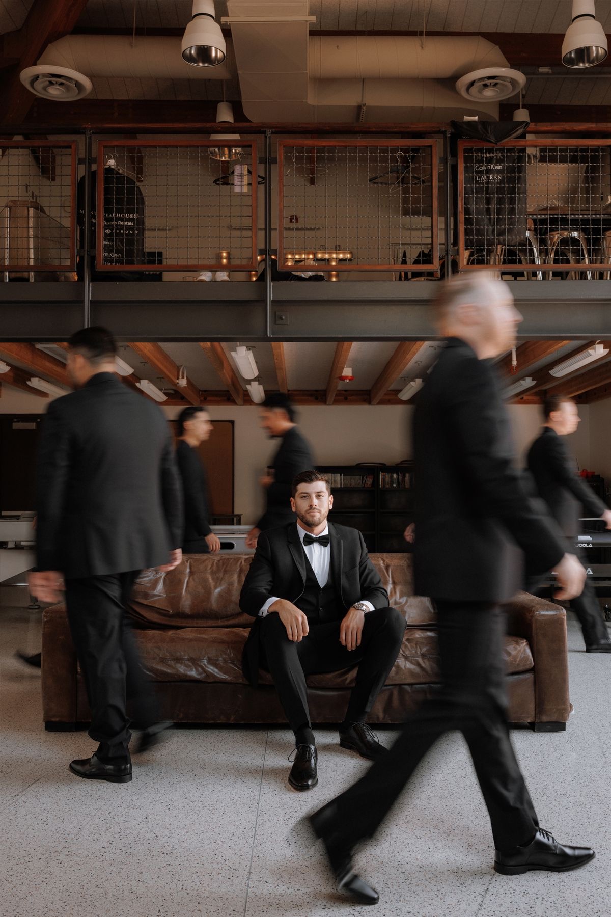 Groom seated with groomsmen walking in motion blur