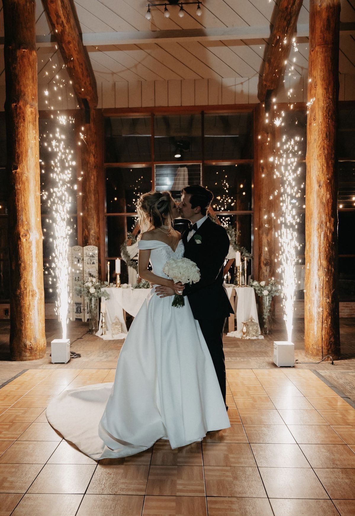 First dance kiss with sparkler fountains in rustic barn