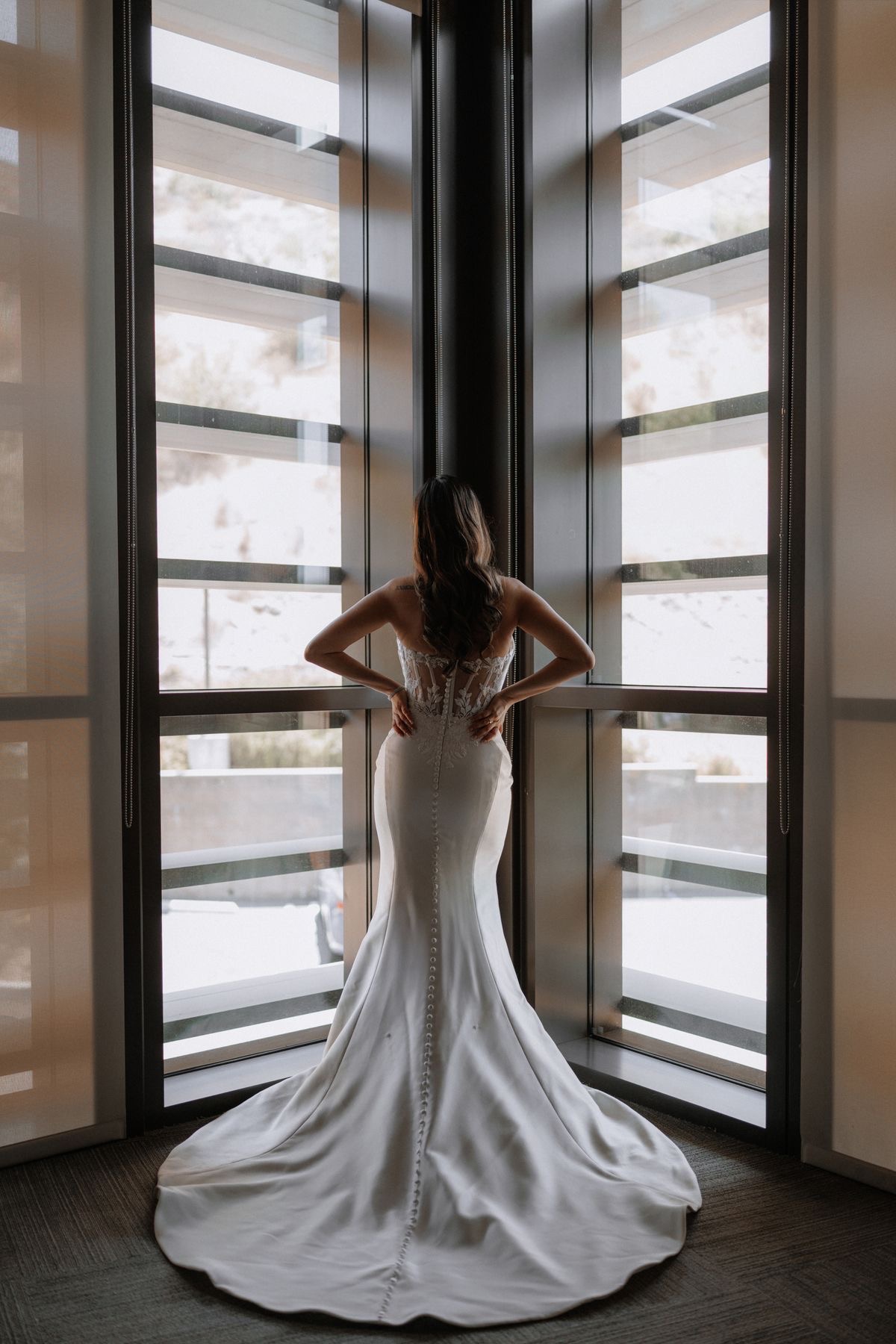 Bride from behind showing dress train at modern window